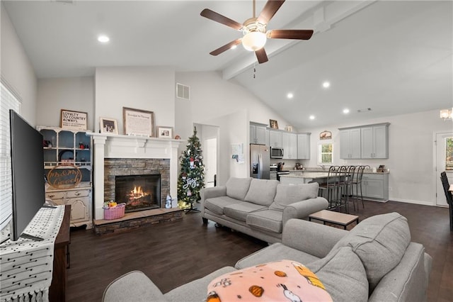 living room featuring ceiling fan, a stone fireplace, dark hardwood / wood-style flooring, beamed ceiling, and high vaulted ceiling