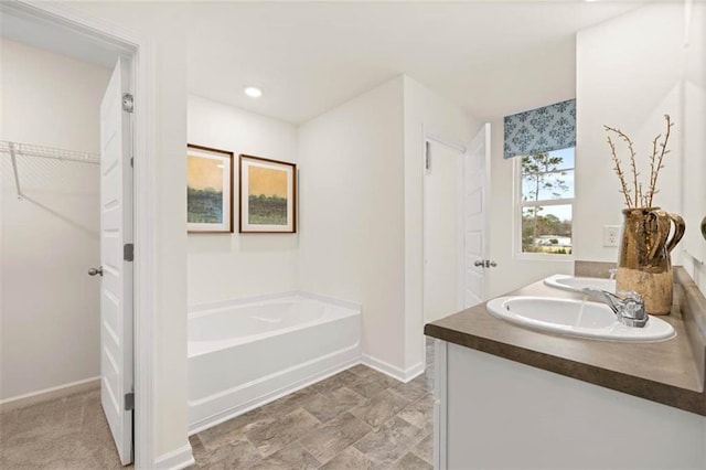 353 Sound Cir, Stockbridge, GA 30281 - bathroom with double vanity, a garden tub, baseboards, and a sink