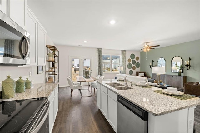 353 Sound Cir, Stockbridge, GA 30281 - kitchen with dark wood-style floors, stainless steel appliances, a sink, open floor plan, and white cabinetry