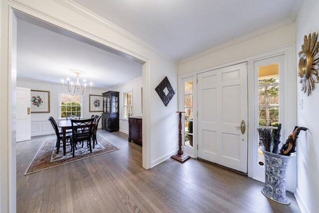 entrance foyer featuring dark wood-type flooring, crown molding, and an inviting chandelier