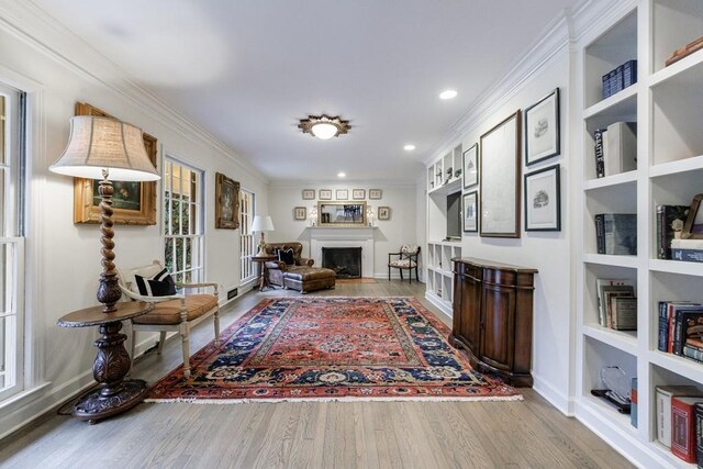 living room featuring hardwood / wood-style floors, built in features, and ornamental molding