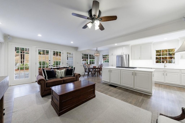 living room featuring ceiling fan, a healthy amount of sunlight, french doors, and light hardwood / wood-style flooring