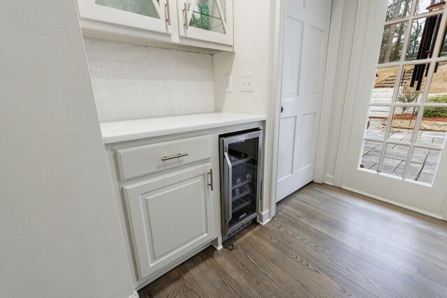 bar featuring white cabinets, dark hardwood / wood-style flooring, and wine cooler