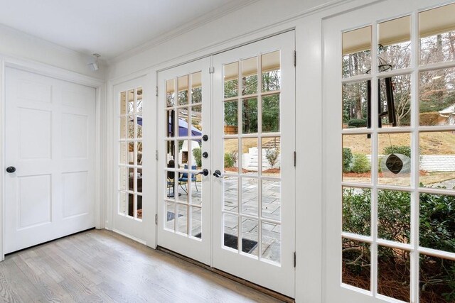 entryway with light wood-type flooring, french doors, and crown molding