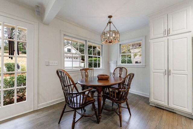 dining room featuring dark hardwood / wood-style flooring, beamed ceiling, an inviting chandelier, and ornamental molding