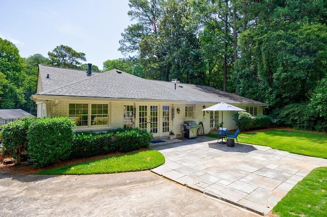 rear view of property with french doors, a patio area, and a yard