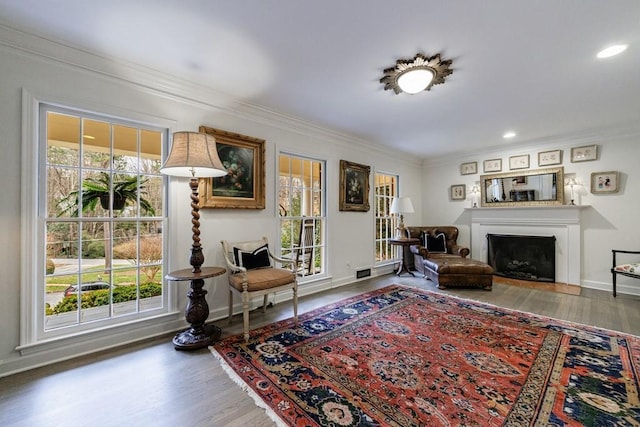 living room featuring hardwood / wood-style flooring, crown molding, and a healthy amount of sunlight