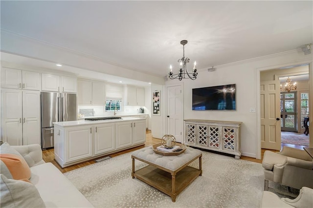 living room with crown molding, a chandelier, and light hardwood / wood-style flooring