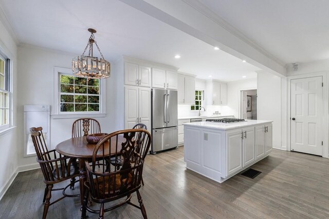 kitchen featuring decorative light fixtures, a kitchen island, light wood-type flooring, appliances with stainless steel finishes, and white cabinets