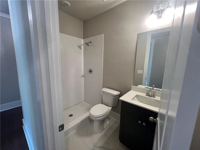 bathroom with tiled shower, vanity, and toilet