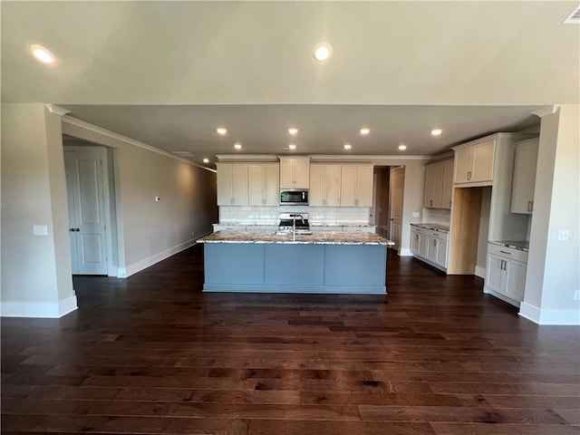 kitchen featuring a center island with sink, backsplash, sink, and dark wood-type flooring