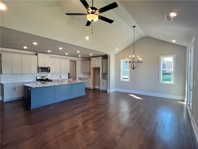 kitchen featuring appliances with stainless steel finishes, an island with sink, white cabinets, ceiling fan with notable chandelier, and dark hardwood / wood-style flooring