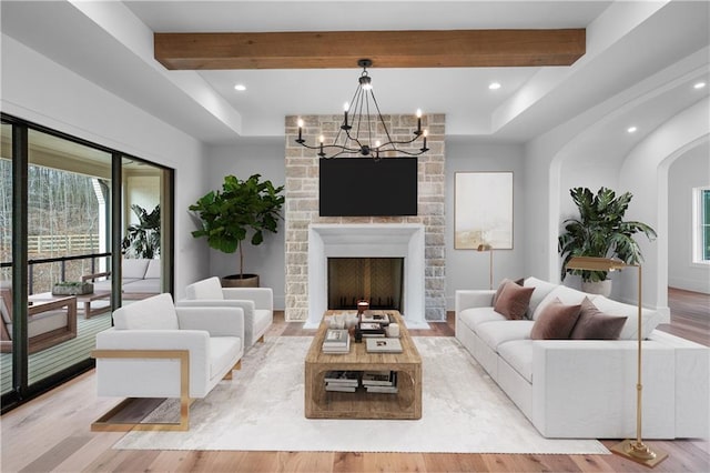 living room featuring light wood-style floors, beam ceiling, and plenty of natural light