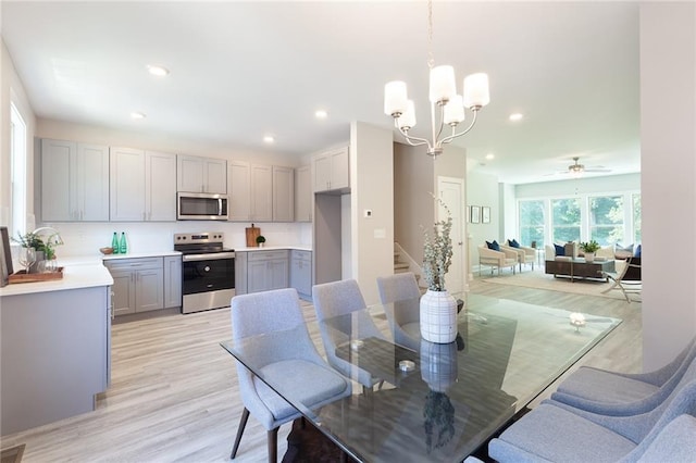 dining room with light wood-type flooring, a notable chandelier, stairway, and recessed lighting