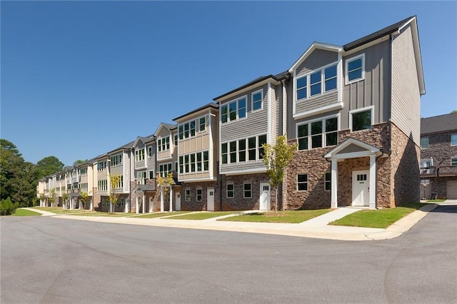 view of front of property with stone siding, a residential view, and board and batten siding