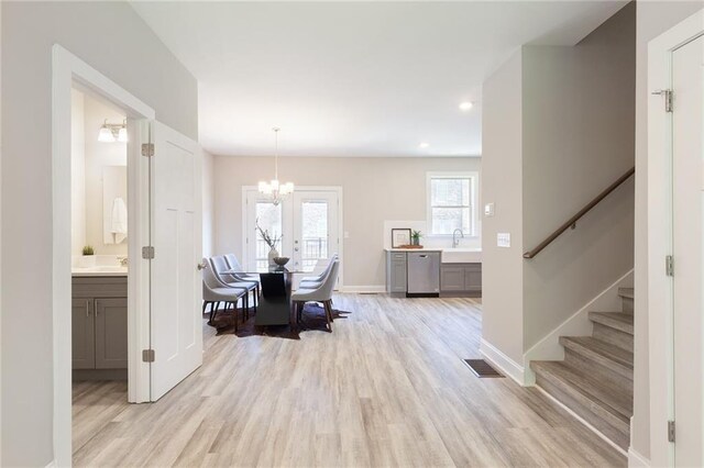 dining space featuring baseboards, stairway, visible vents, and light wood-style floors