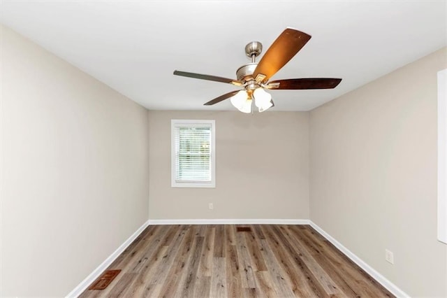 spare room with visible vents, wood finished floors, baseboards, and ceiling fan