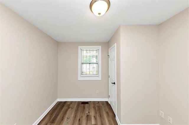 spare room with baseboards and wood finished floors