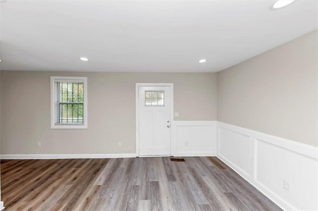 spare room featuring recessed lighting, wood finished floors, wainscoting, and a decorative wall