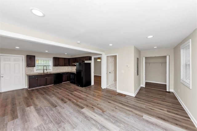 kitchen with tasteful backsplash, dark brown cabinets, light countertops, black appliances, and a sink