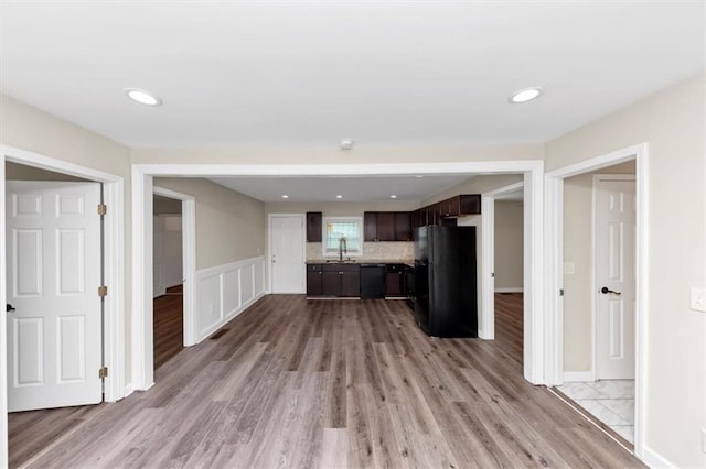 kitchen with black appliances, a sink, light wood-style floors, light countertops, and dark brown cabinets