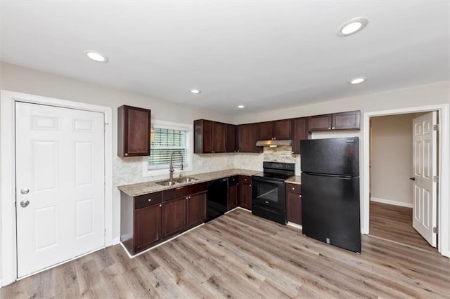 kitchen with under cabinet range hood, dark brown cabinetry, light wood-style flooring, black appliances, and a sink