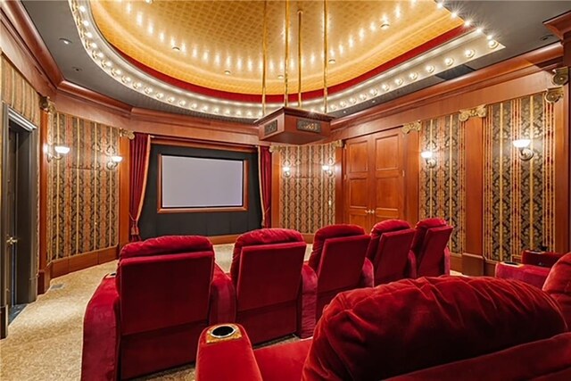 cinema room featuring a raised ceiling, crown molding, and carpet flooring