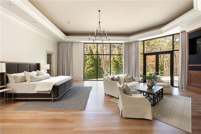 bedroom featuring a raised ceiling, an inviting chandelier, crown molding, wood finished floors, and access to exterior