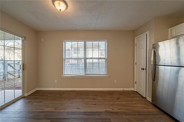 unfurnished dining area featuring dark hardwood / wood-style flooring, plenty of natural light, and a textured ceiling