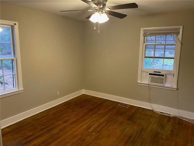 unfurnished room featuring baseboards, visible vents, dark wood finished floors, and a wealth of natural light