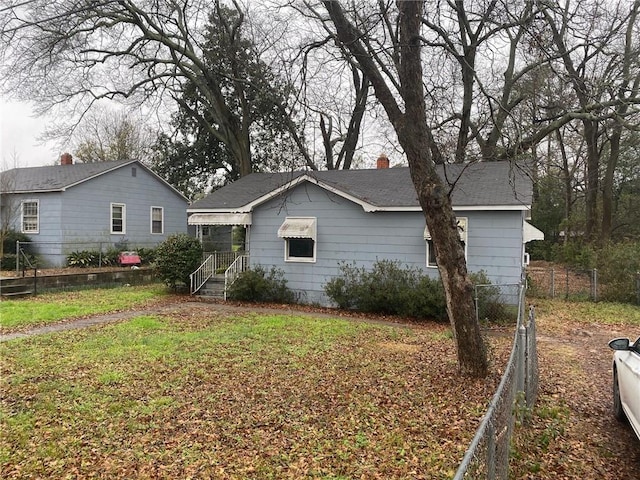 view of side of property with roof with shingles, a chimney, and fence