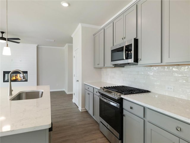 kitchen with light stone countertops, appliances with stainless steel finishes, sink, decorative light fixtures, and a fireplace