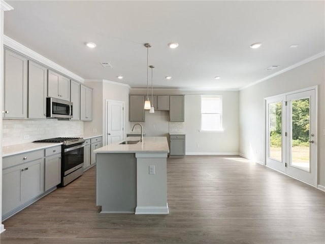 kitchen with sink, decorative light fixtures, gray cabinets, a kitchen island with sink, and appliances with stainless steel finishes