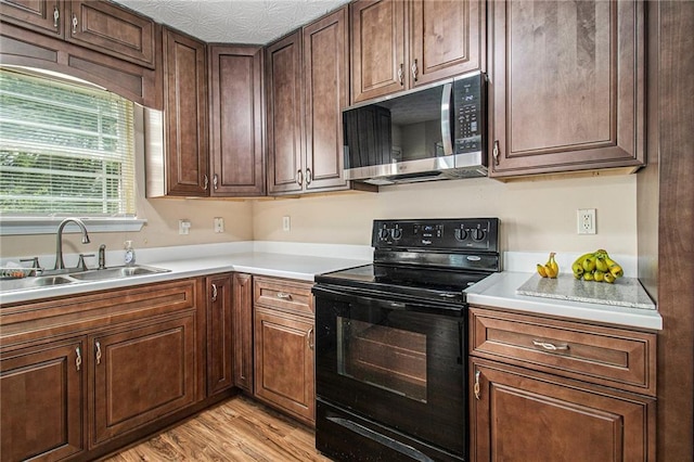 45 Ratliff Dr, Covington, GA 30016 - kitchen featuring stainless steel microwave, black / electric stove, light countertops, and light wood-style flooring