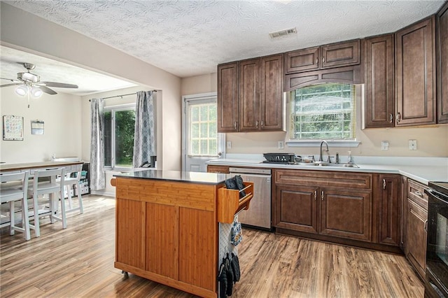 45 Ratliff Dr, Covington, GA 30016 - kitchen with stainless steel dishwasher, light wood-style floors, a ceiling fan, a center island, and dark brown cabinets