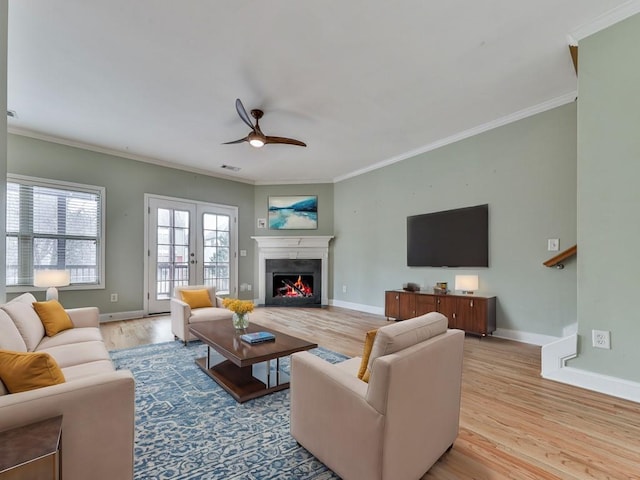 living room with crown molding, french doors, ceiling fan, and light wood-type flooring