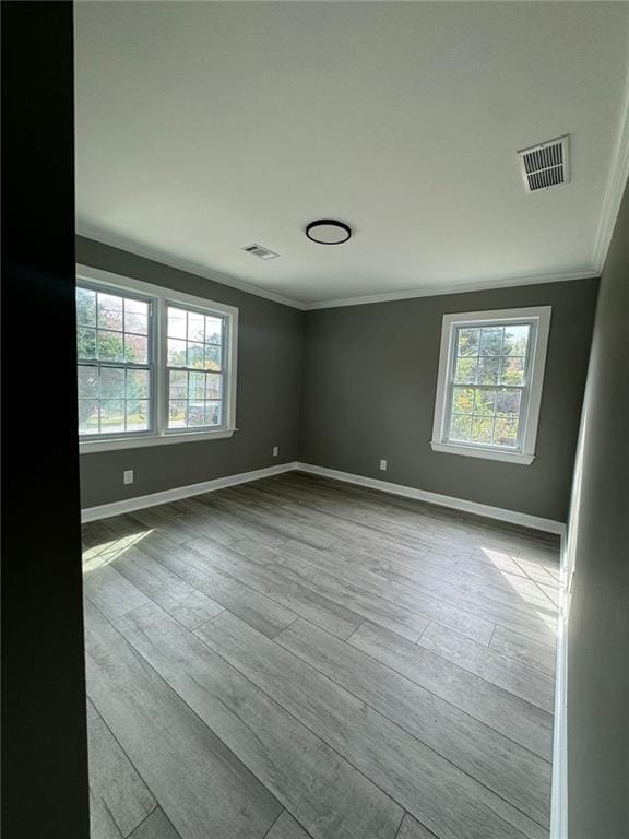 unfurnished room with ornamental molding, baseboards, and wood finished floors