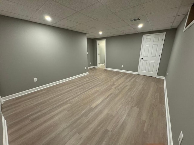 finished basement featuring wood finished floors, a drop ceiling, and baseboards