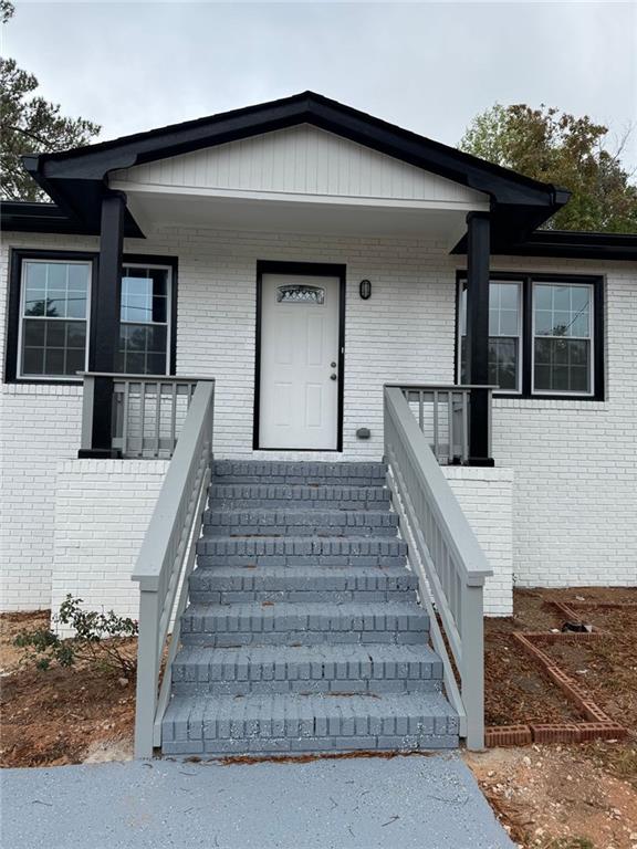 doorway to property featuring covered porch and brick siding
