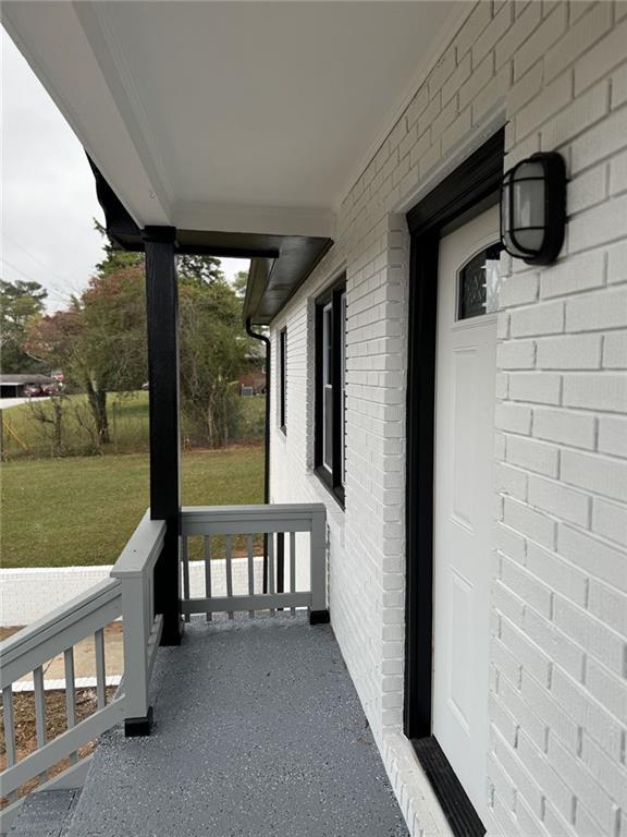 doorway to property featuring brick siding, a lawn, and a porch