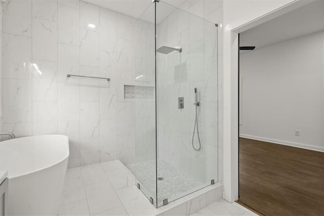 bathroom featuring tile walls, marble finish floor, a marble finish shower, and a freestanding bath