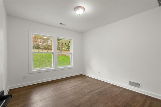 empty room with baseboards, visible vents, and dark wood-style flooring