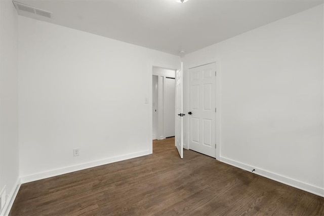 empty room featuring baseboards and dark wood-type flooring