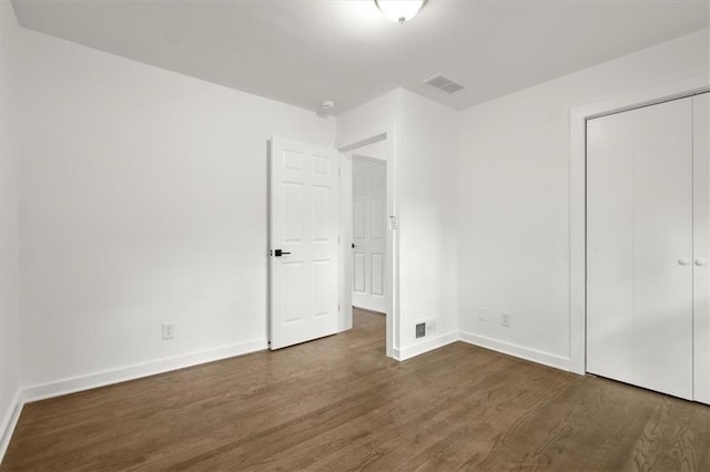 unfurnished bedroom featuring visible vents, baseboards, and dark wood-type flooring