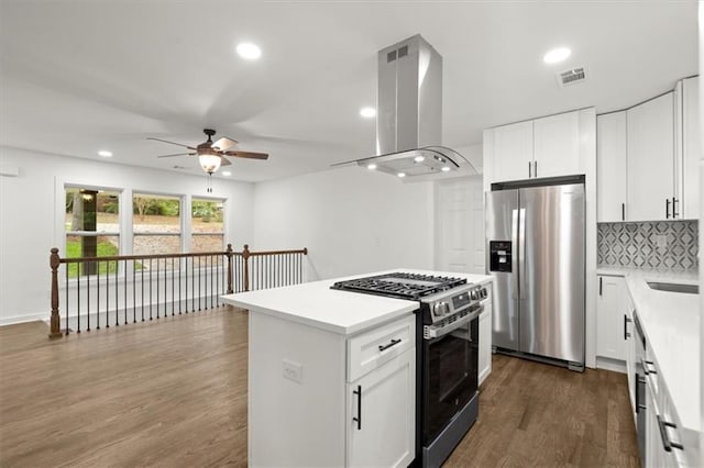 kitchen featuring backsplash, island exhaust hood, stainless steel appliances, and light countertops