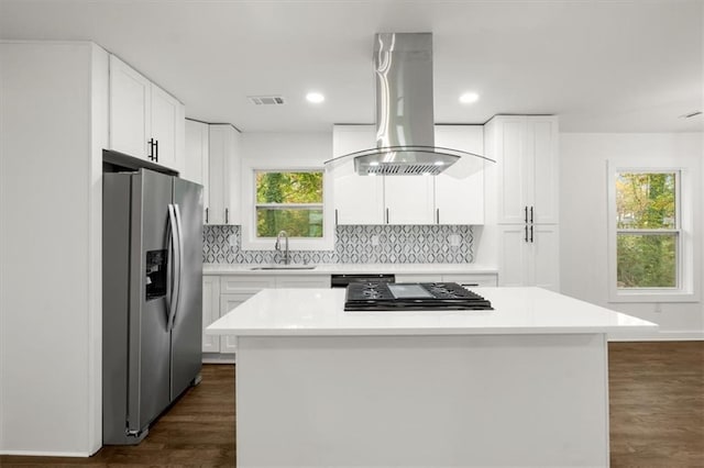 kitchen with island exhaust hood, dark wood-style flooring, a sink, stainless steel fridge, and backsplash