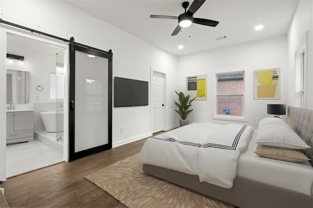 bedroom featuring visible vents, a barn door, recessed lighting, ensuite bathroom, and wood finished floors