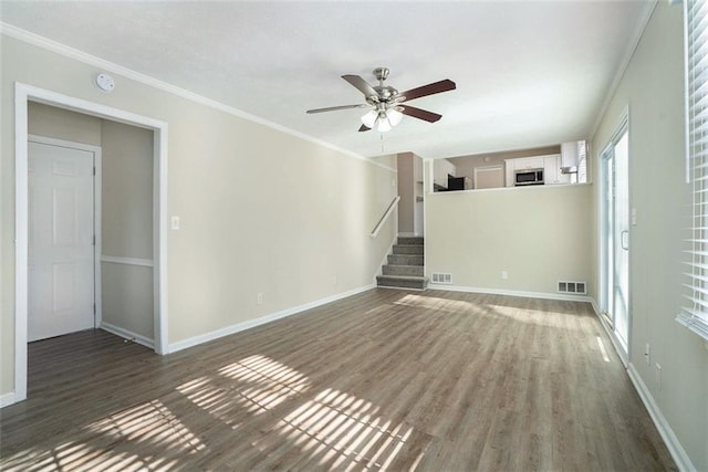 unfurnished living room with ceiling fan, crown molding, and dark wood-type flooring