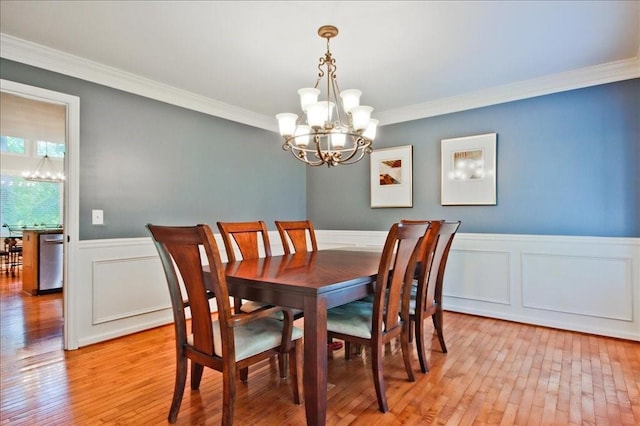 dining space featuring wainscoting, a notable chandelier, light wood-style flooring, and crown molding