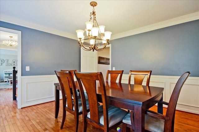 dining room with light wood finished floors, a notable chandelier, and ornamental molding